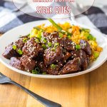 garlic butter steak bites on a white plate with a side of rice