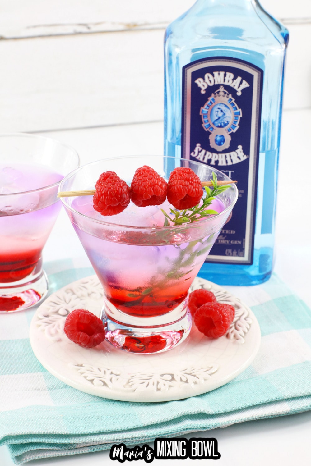 gin berry cocktail in a cocktail glass garnished with raspberries on a toothpick