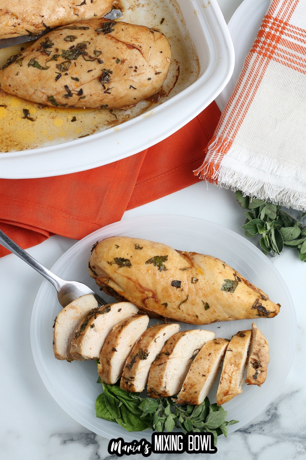 two chicken breasts on a plate. One is sliced and one is whole