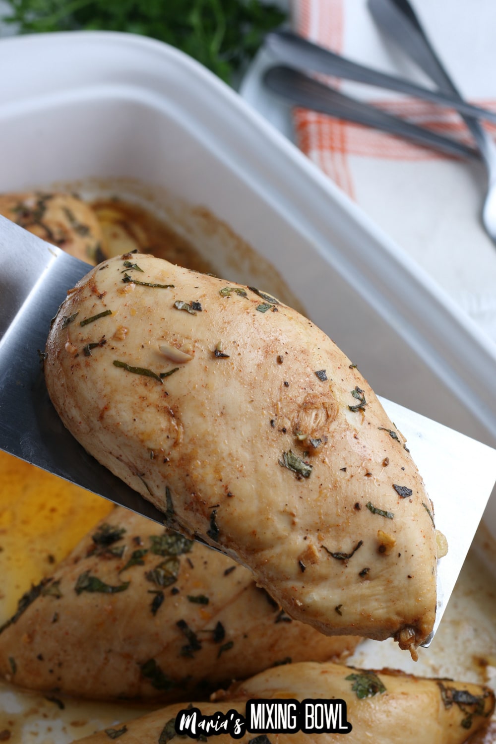 baked chicken breasts held in the air on a metal spatula