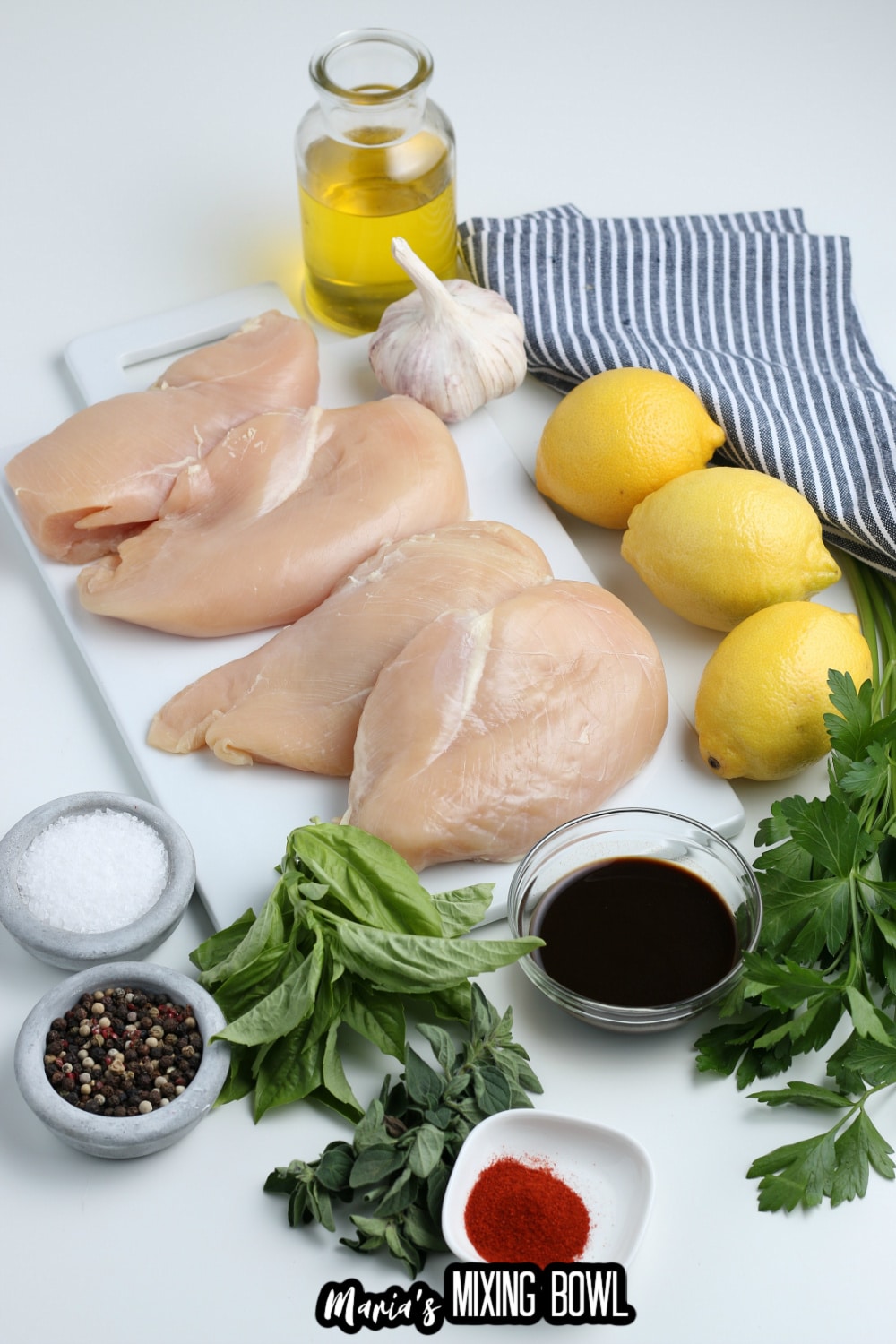 chicken breasts, garlic, lemon, oil, salt, pepper, paprika and oil on a white background