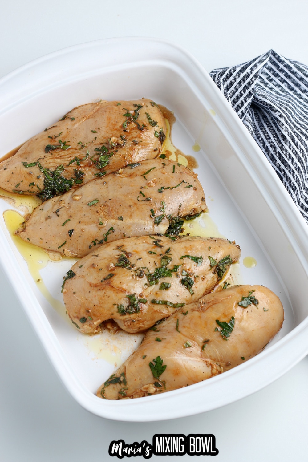 raw chicken breasts in seasoned in a white baking dish