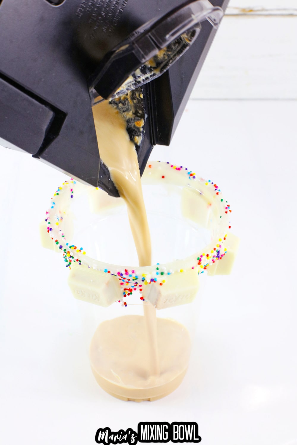 coffee shake being poured into a rimmed glass