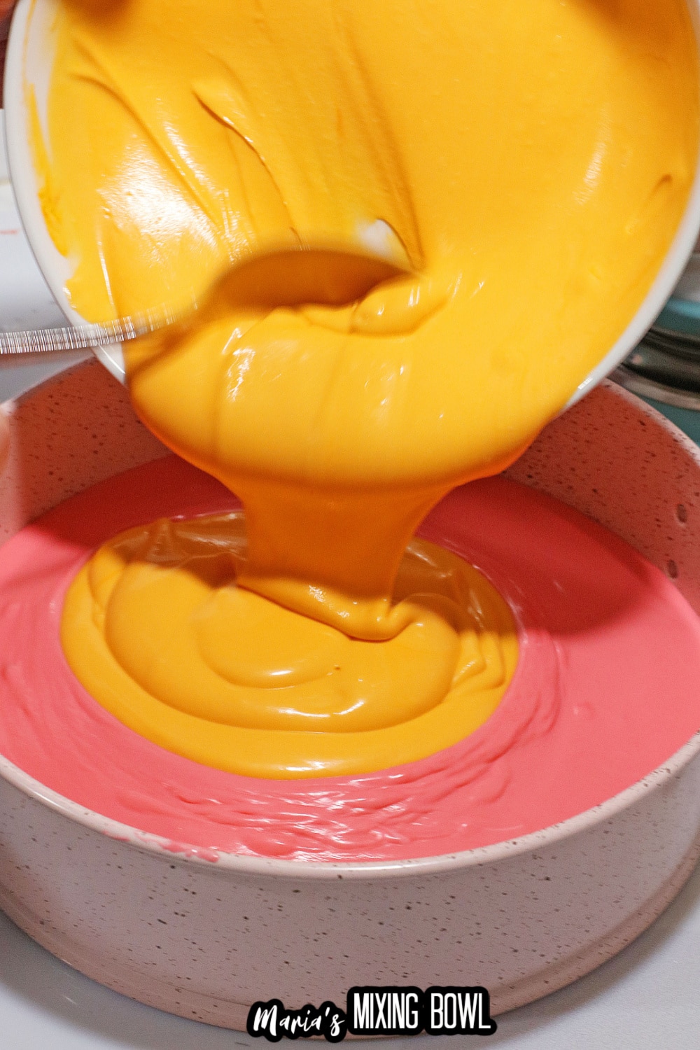orange and pink batter being added to a springform pan