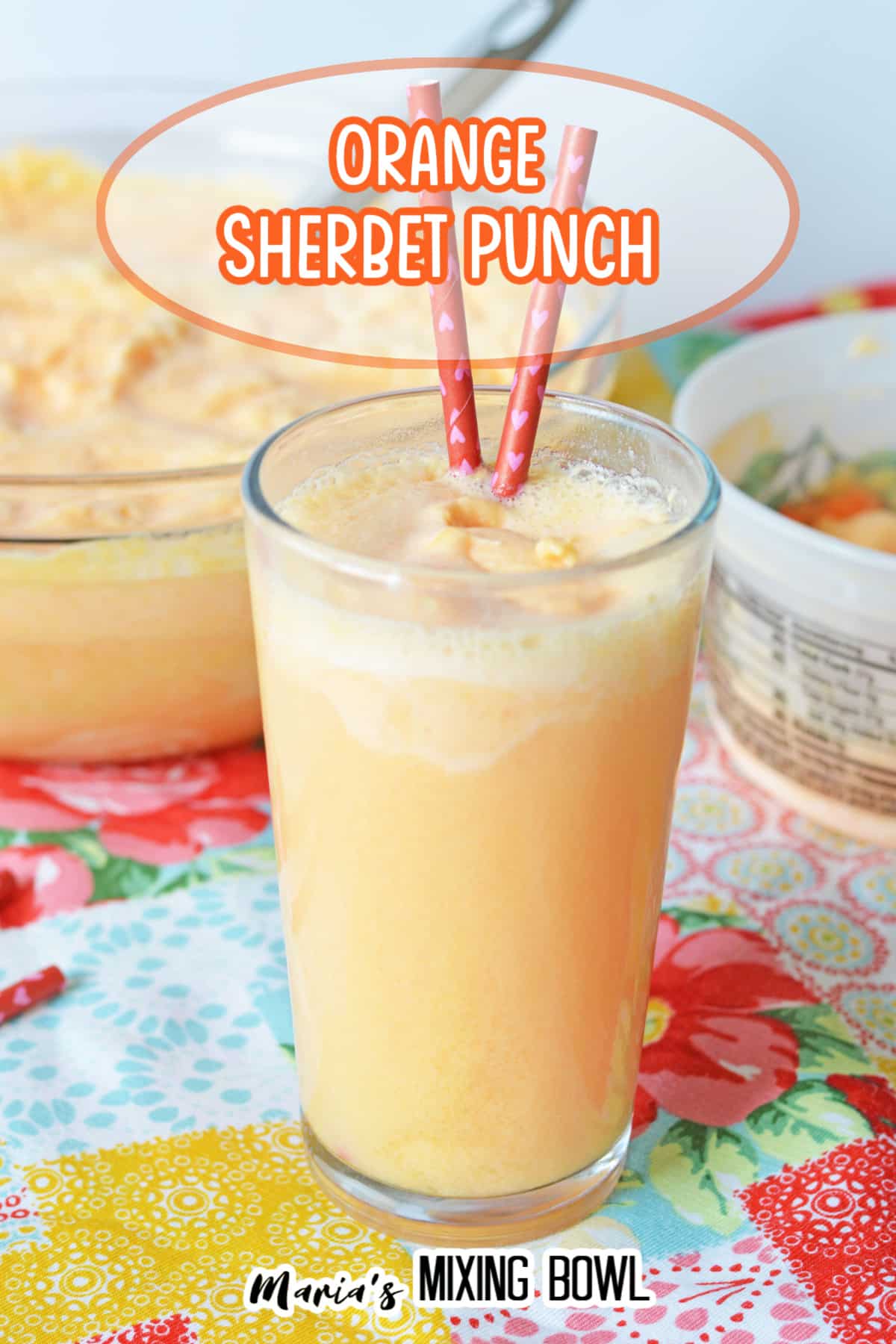 glass of orange sherbet with two straws in it.
