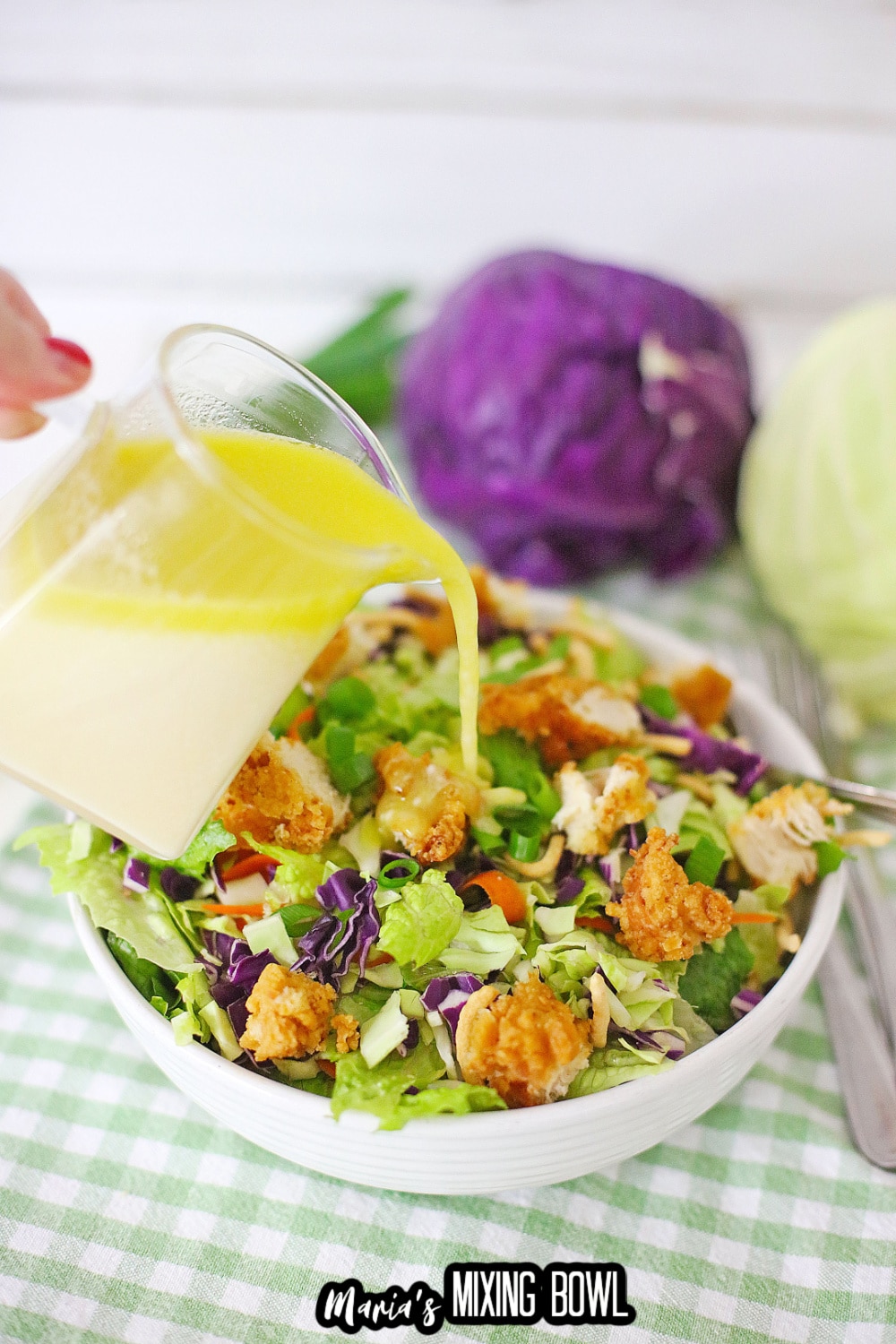 dressing being poured over a white bowl filled with salad