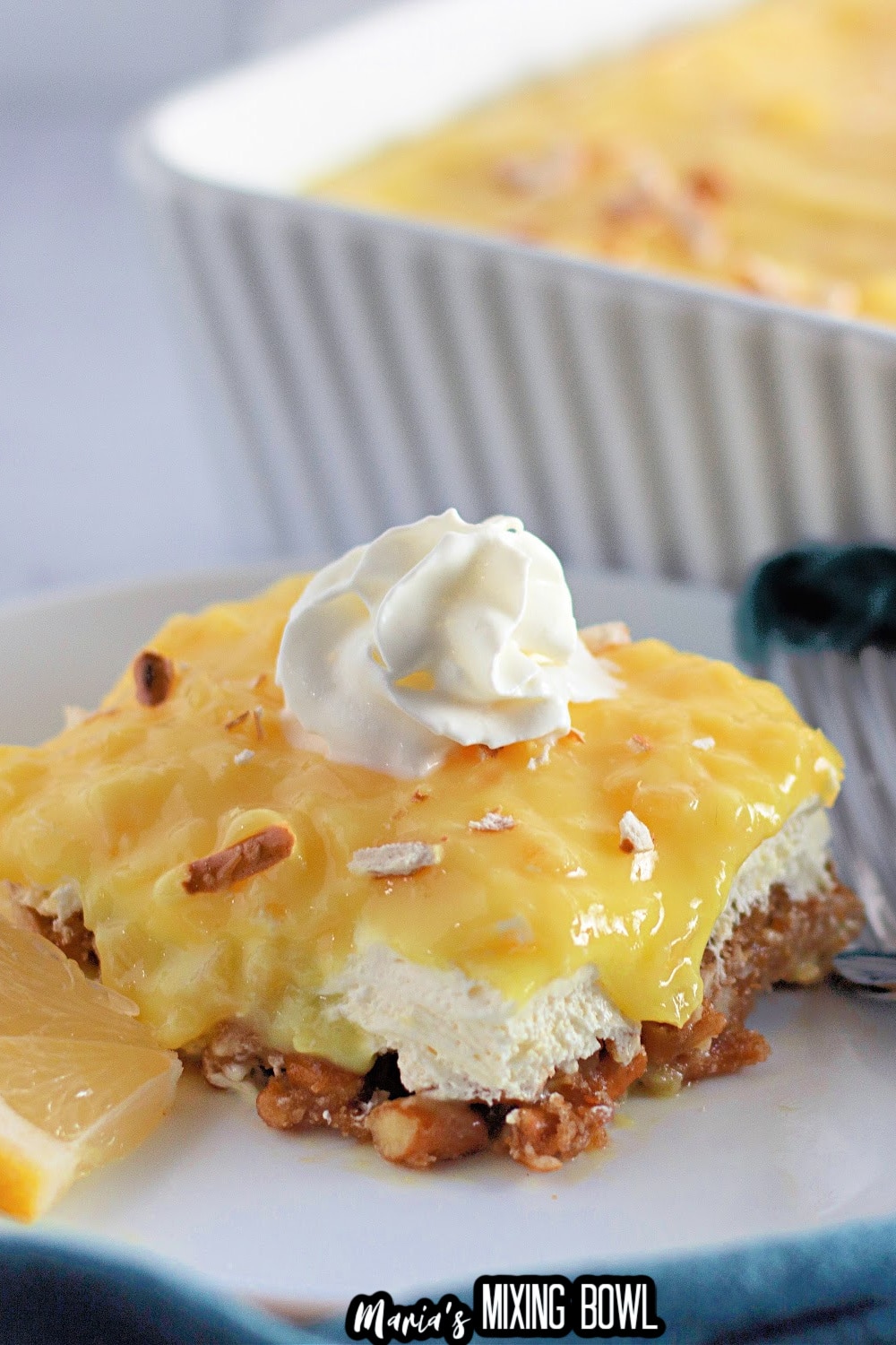 slice of pineapple pretzel salad on a white plate with a sliver fork.
