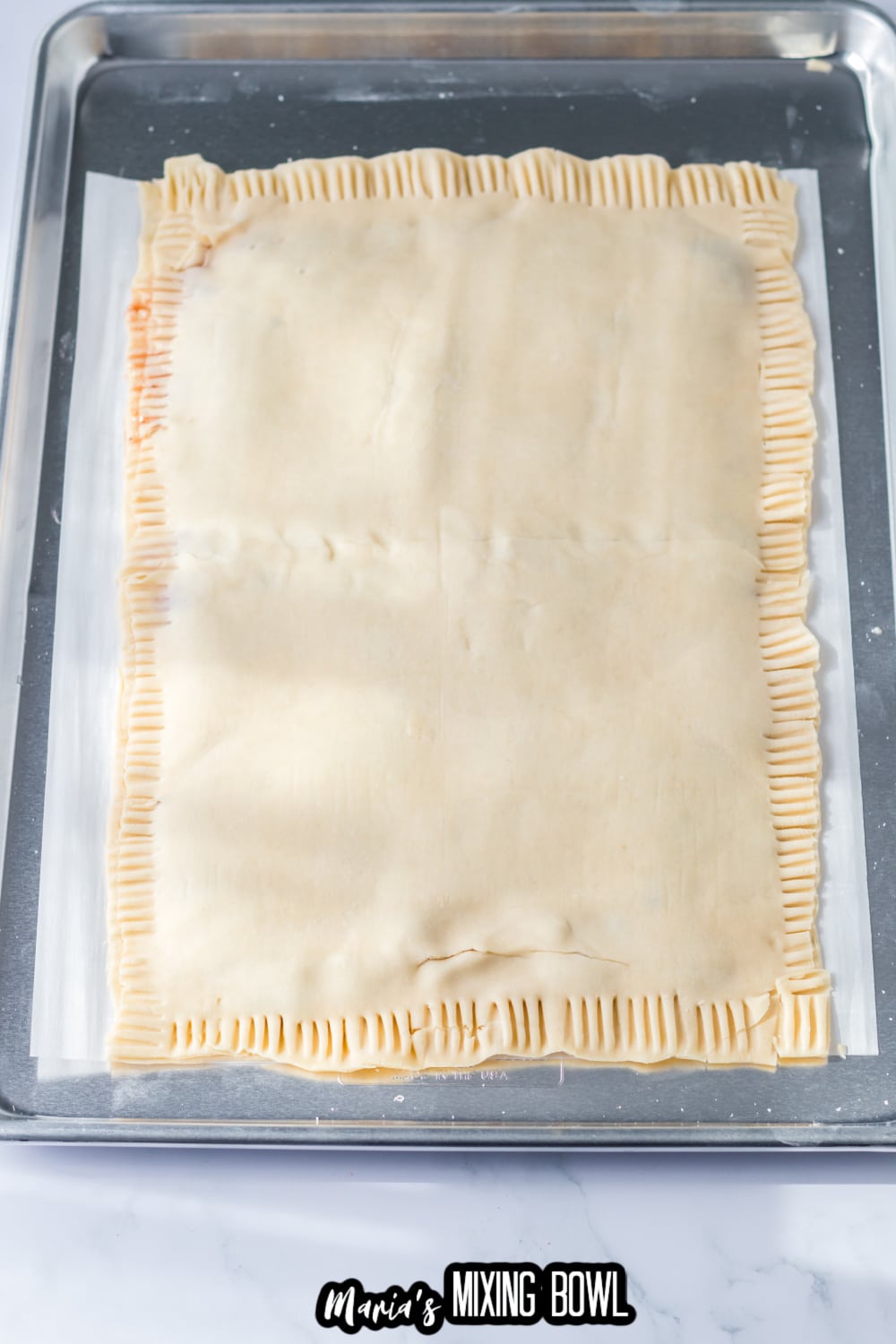 pie crusts filled with jam on a parchment lined baking sheet