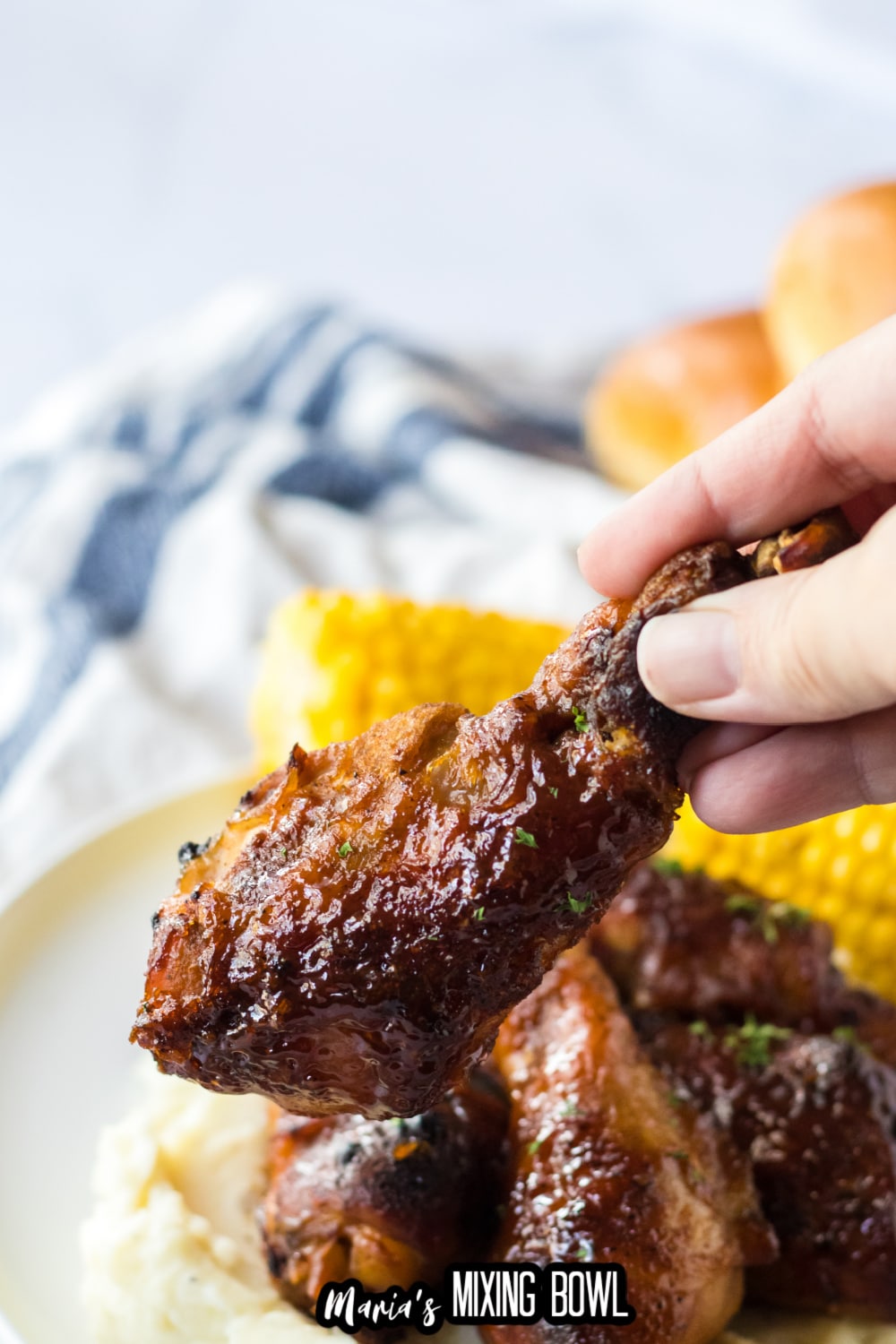 chicken drumstick held in the air in the woman's hand