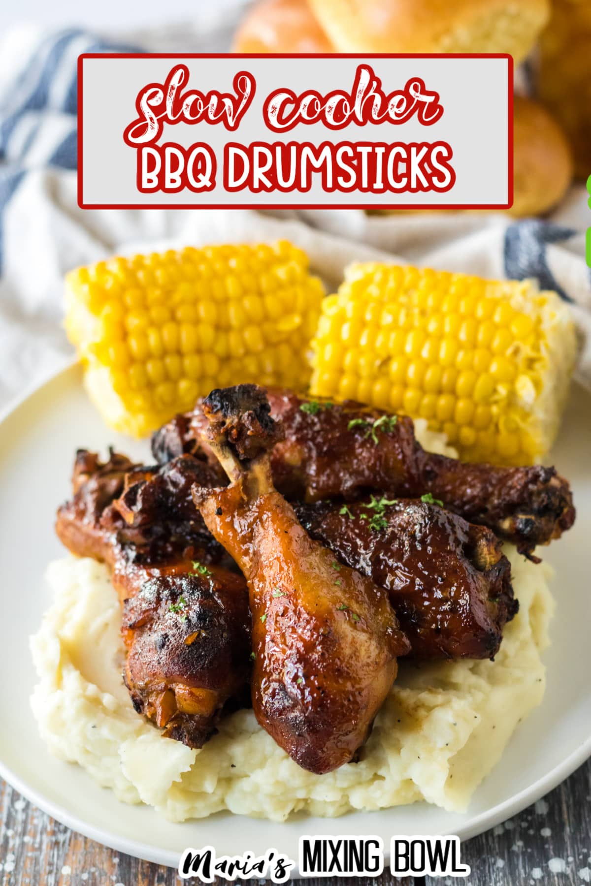 four chicken drumsticks on top of a bed of mashed potatoes with corn cobs in the background