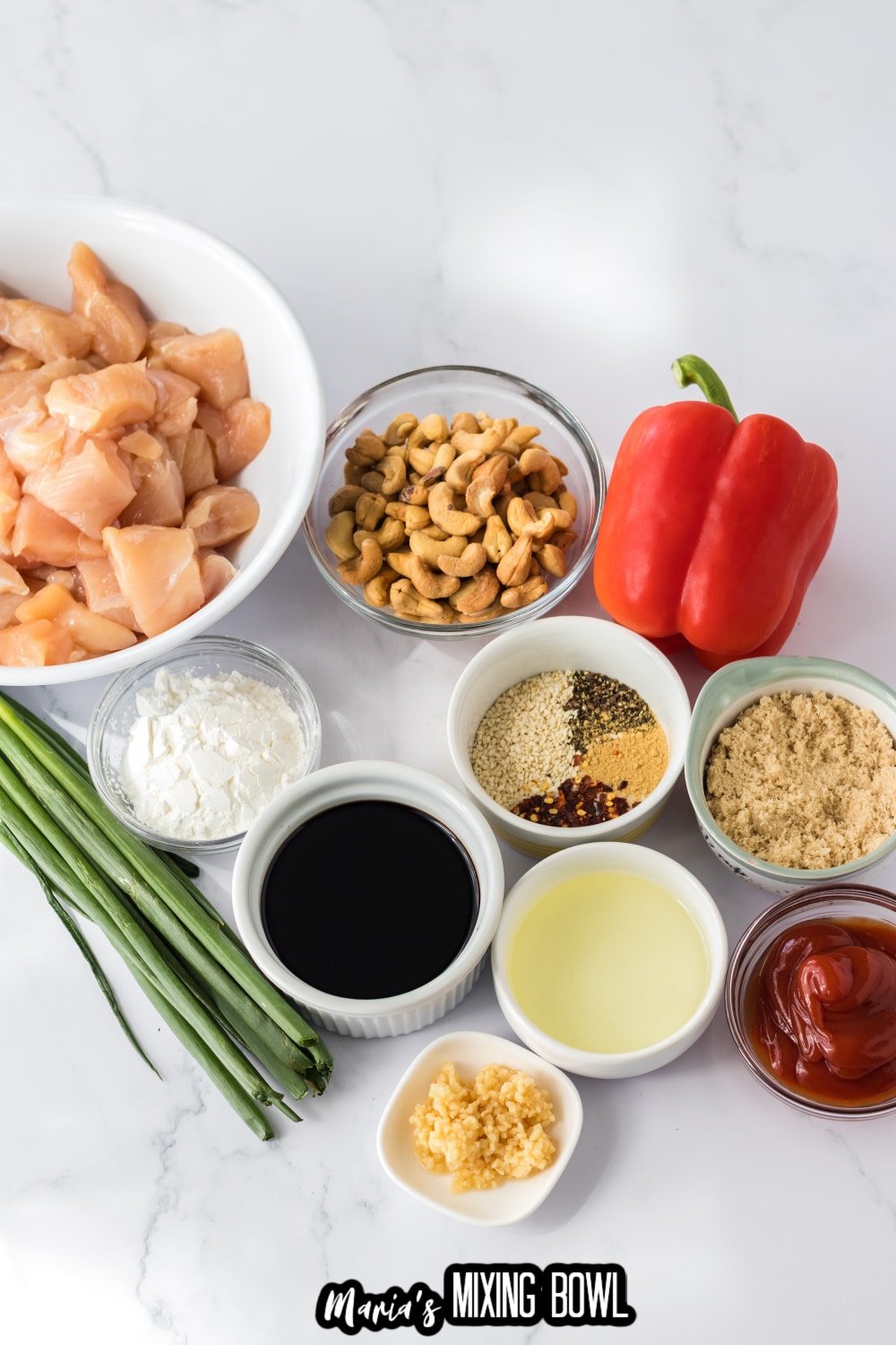 diced chicken, green onions,, flour, cashews, red pepper, seasonings, garlic, brown sugar, soy sauce and ketchup on a white background
