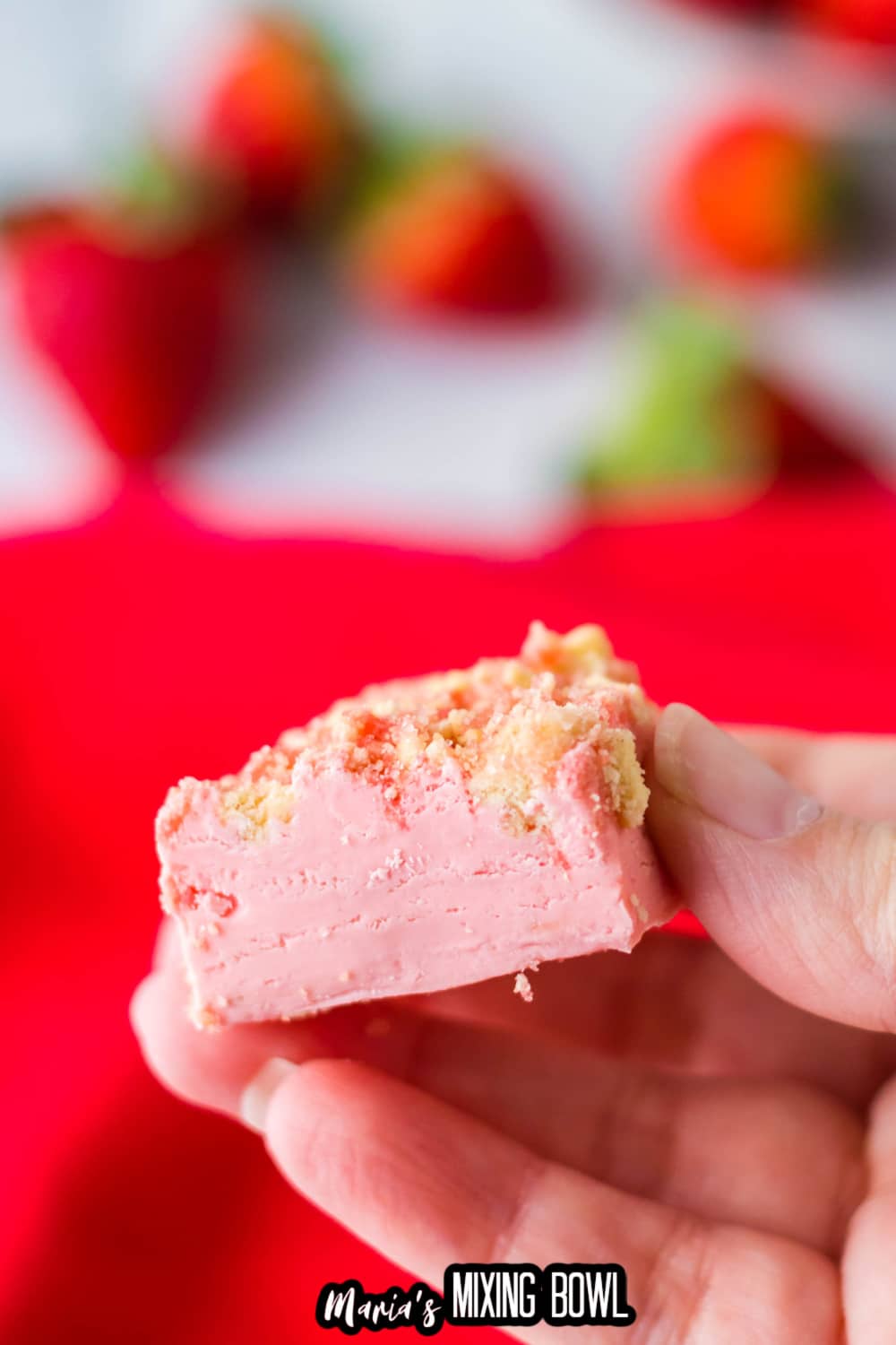 piece of strawberry fudge held in the air in a woman fingers