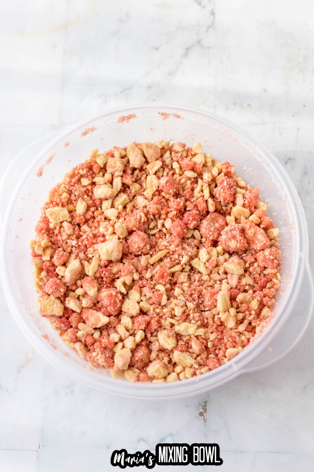 golden oreos being mixed with strawberry gelatin in a clear plastic bowl