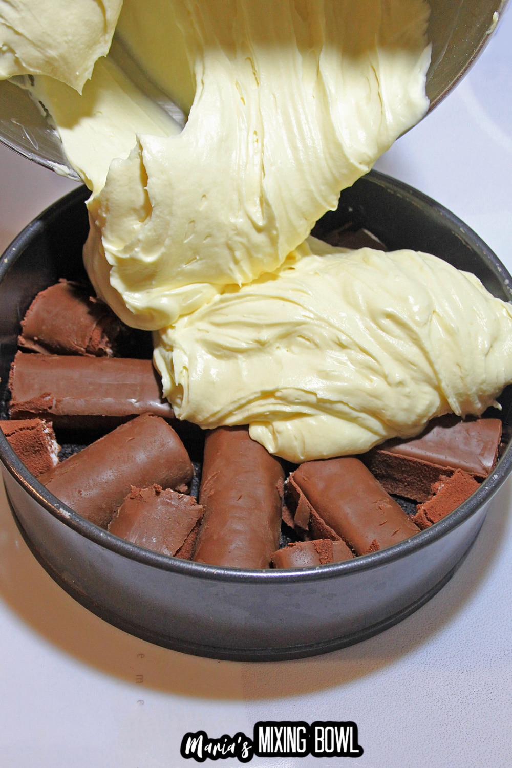 batter being poured on top of swiss rolls in a springform pan