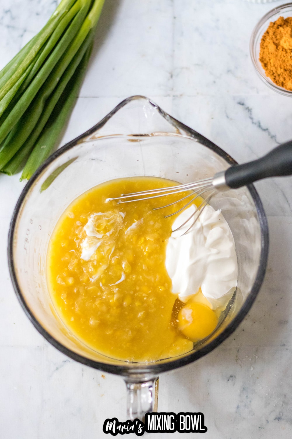 creamed corn, egg, and sour cream in a glass mixing bowl