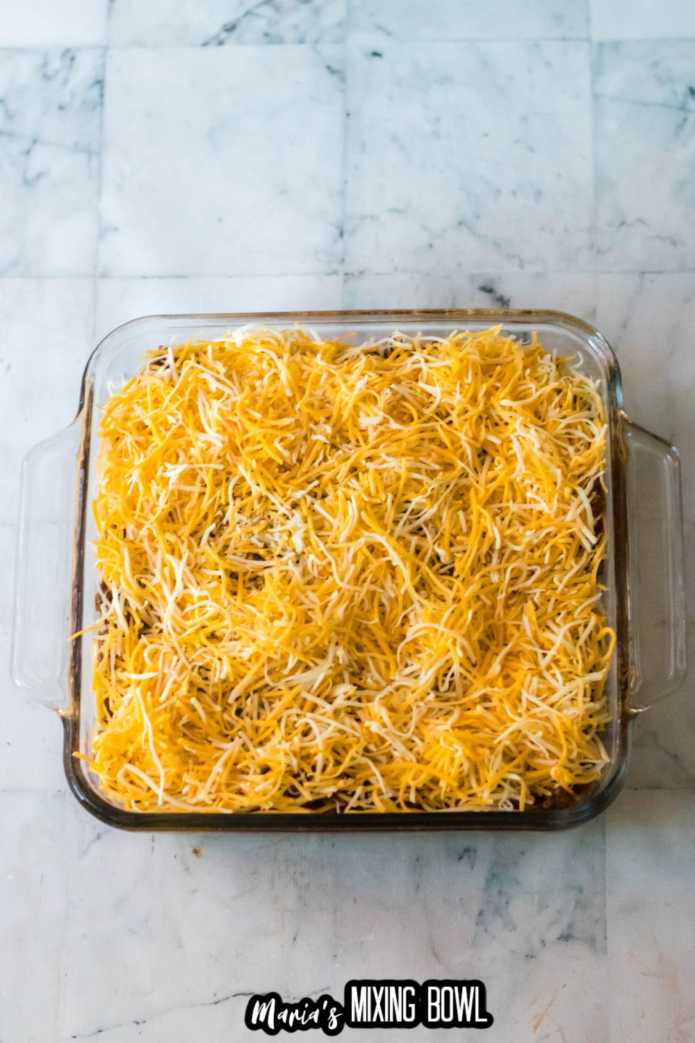 cheese sprinkles on top of a casserole in a glass baking dish