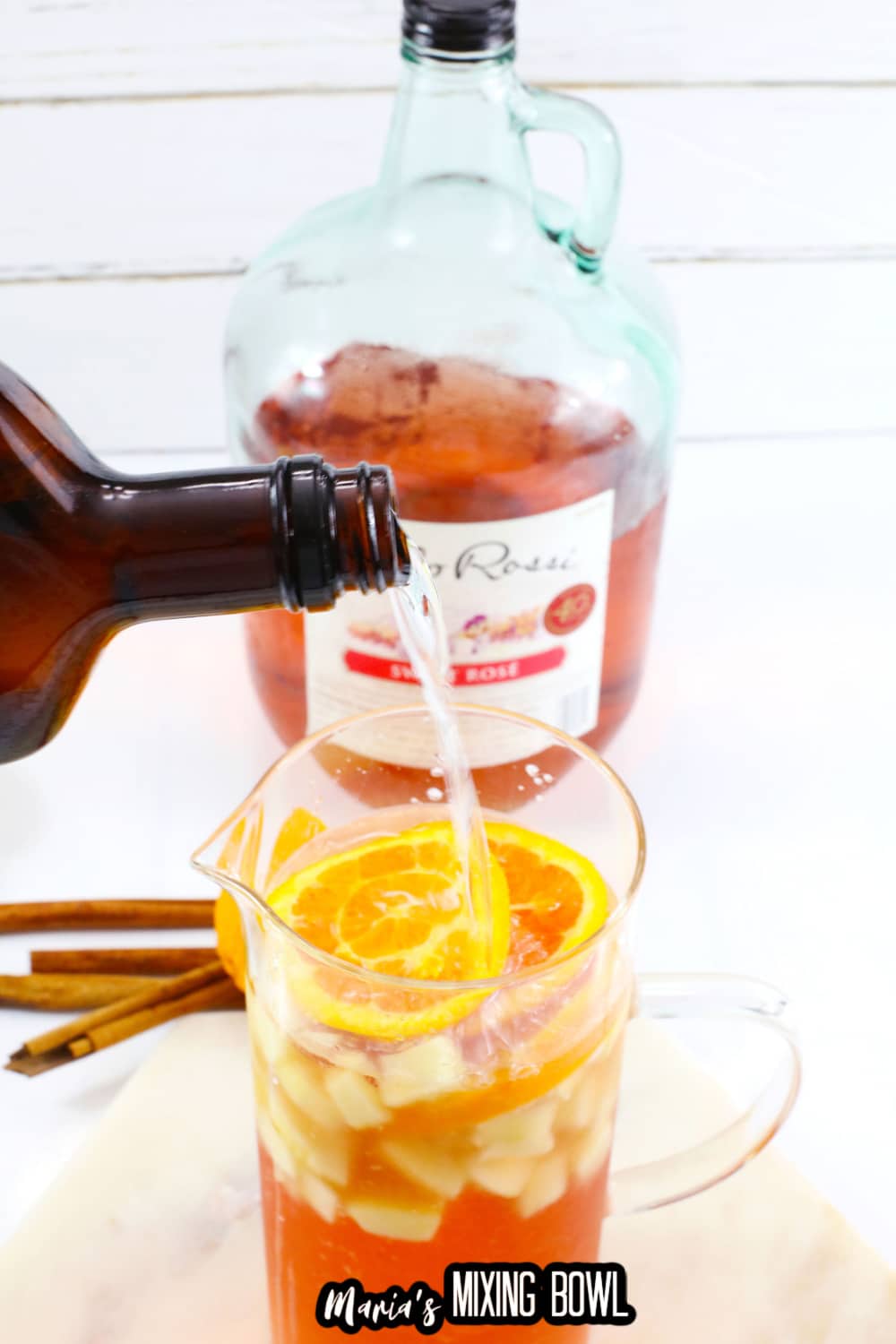 triple sec being poured into a pitcher of sangria