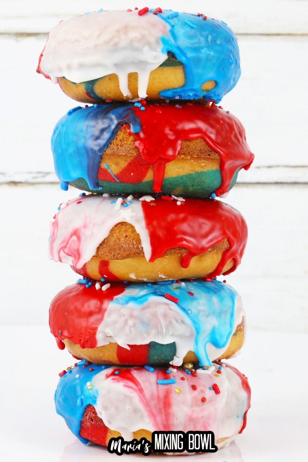five donuts stacked on top of each on a white wooden background