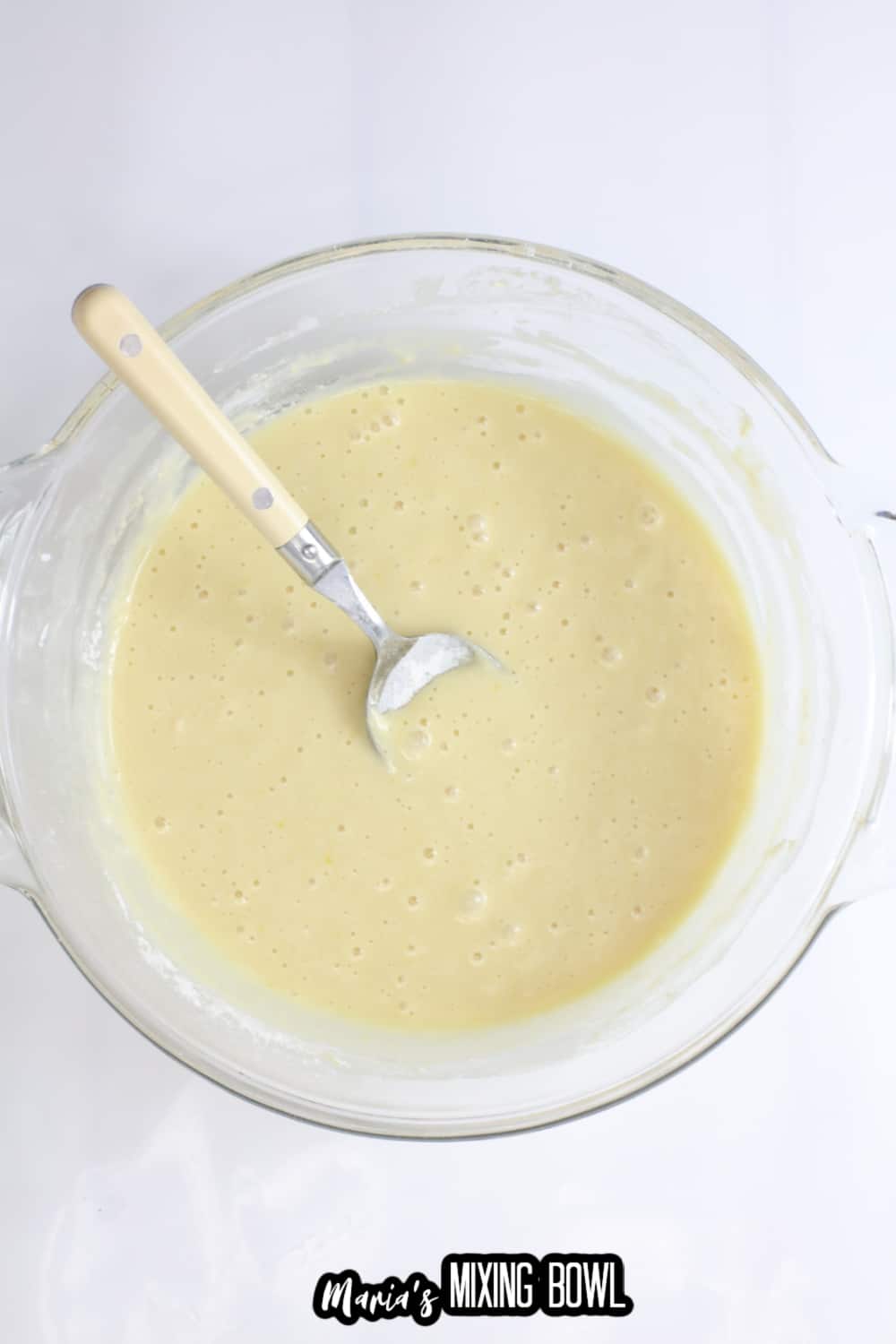 batter in a large glass mixing bowl with a spoon