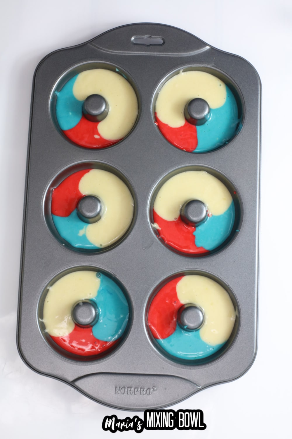 red white and blue donut batter in a donut pan