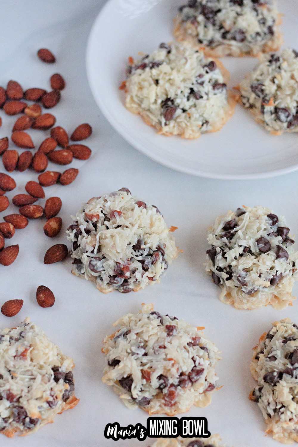 almond joy cookies on a white background with a pile of almonds