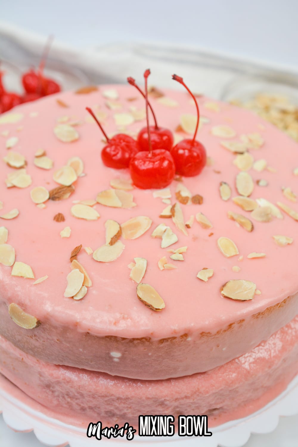 uncut cherry almond cake on a white cake stand