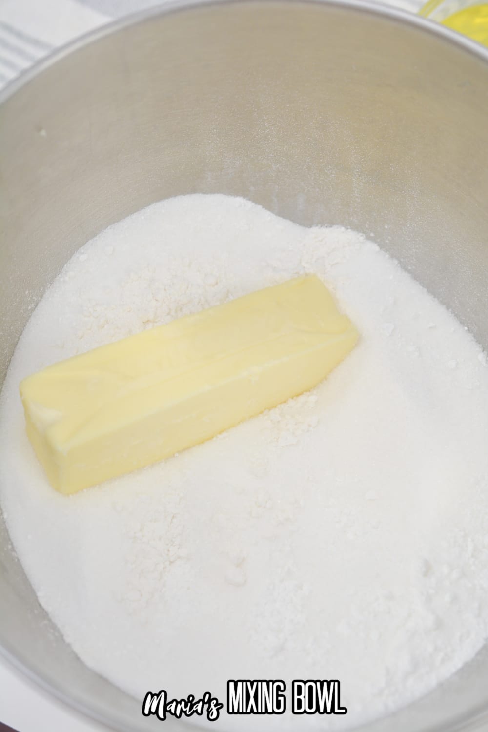 butter and sugar being mixed in a stainless steel mixing bowl