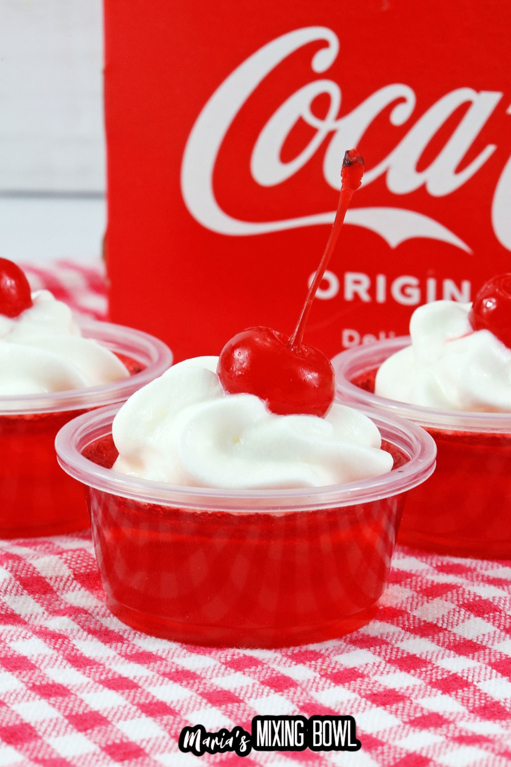 close up of cherry coke jello shots on a red and white kitchen towel