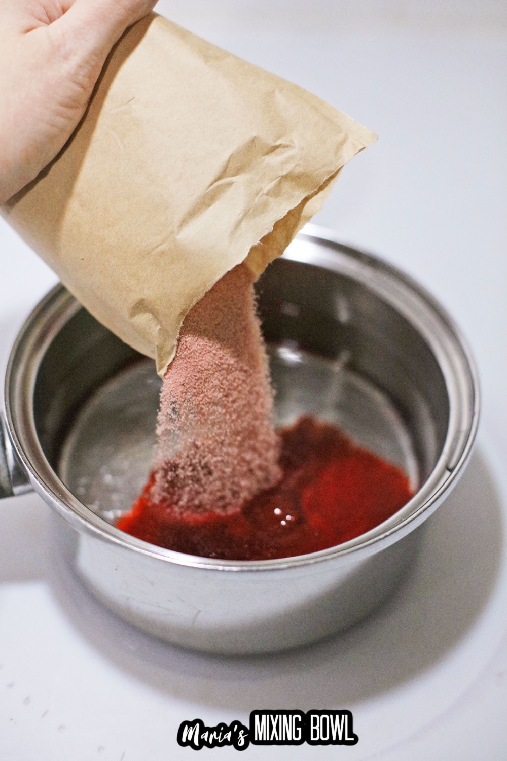 gelatin being poured into a small saucepan full of boiling water