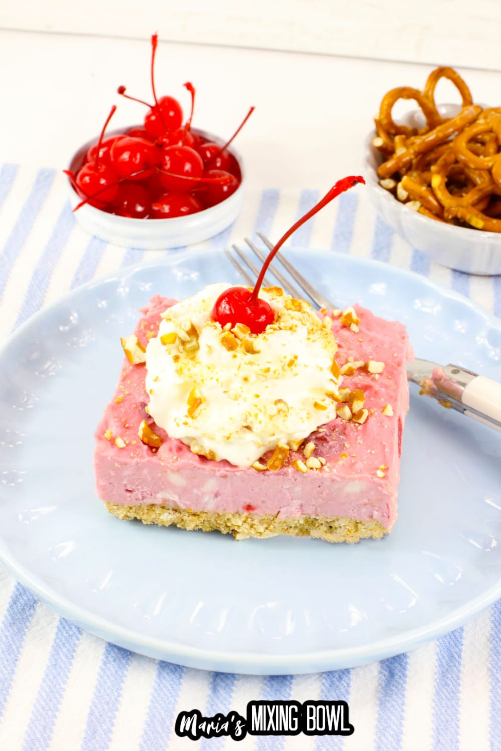 slice of cherry delight on a light blue plate topped with whipped cream and a cherry