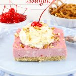 slice of cherry delight on a light blue plate topped with whipped cream and a cherry