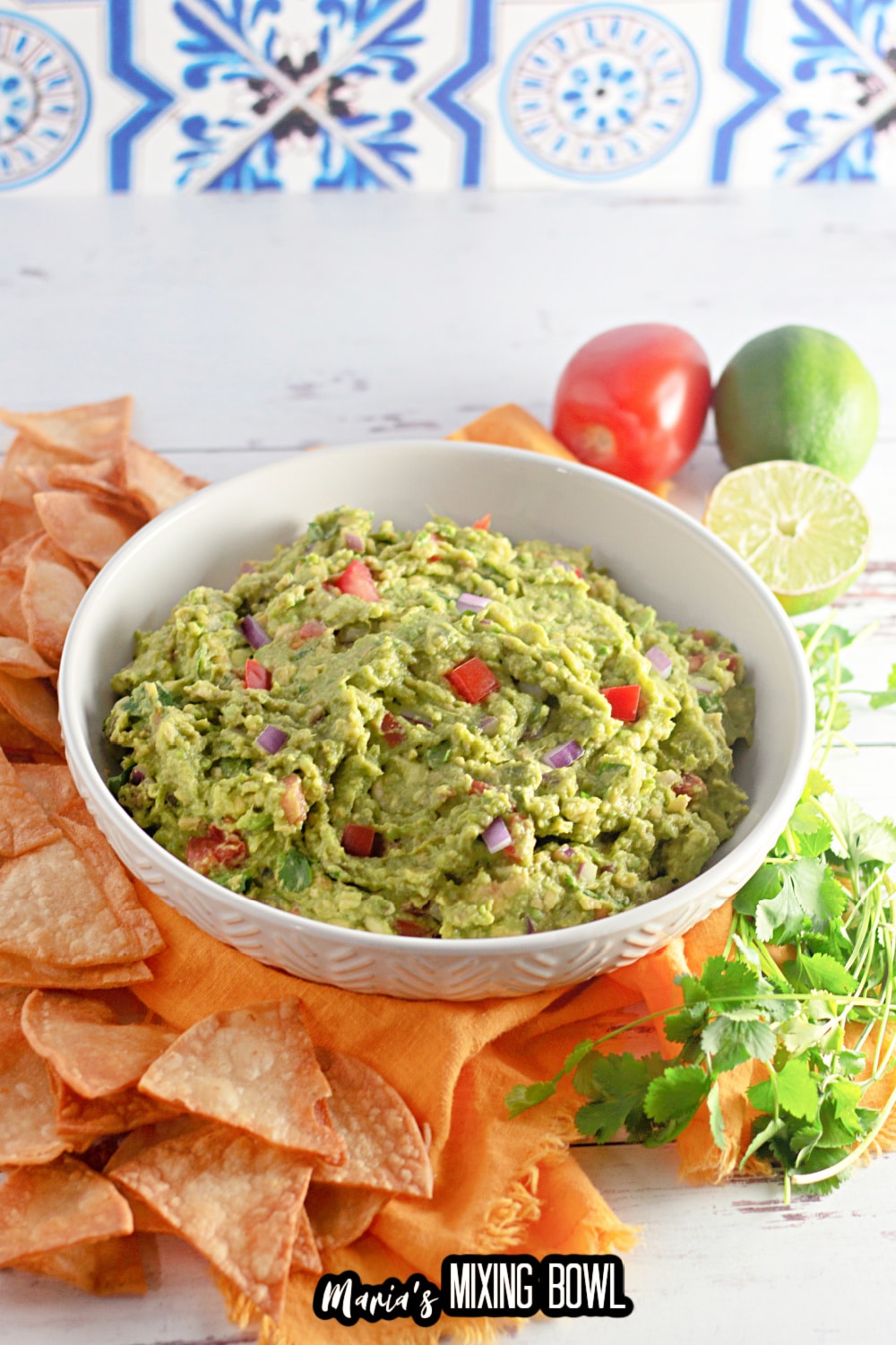 homemade guacamole in a white plate surrounded tortilla chips