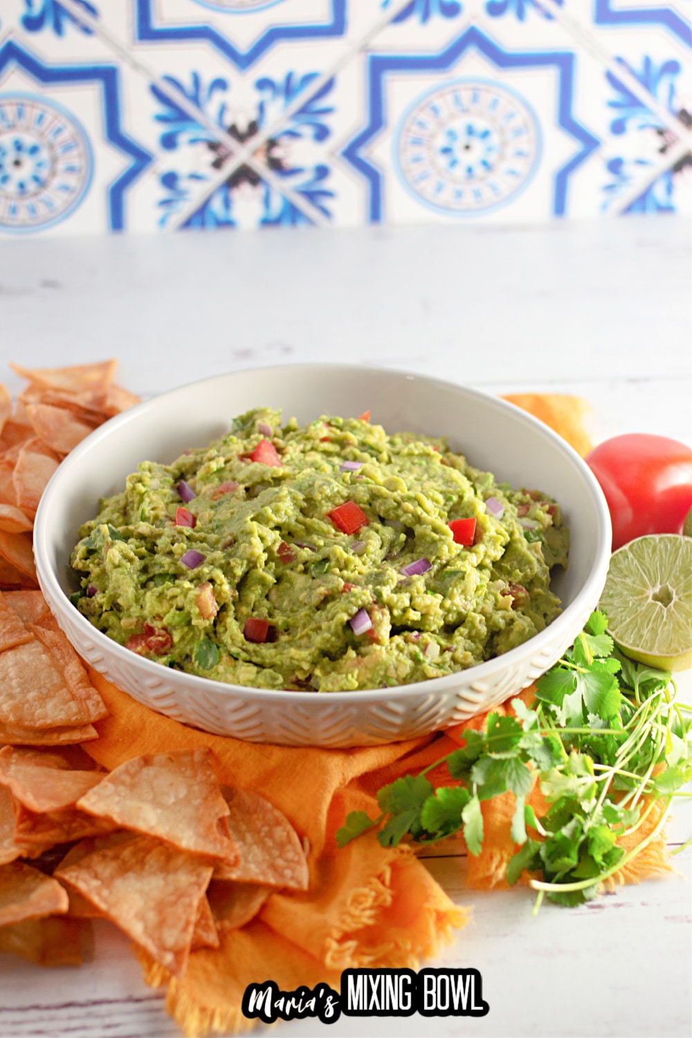 homemade guacamole in a white plate surrounded tortilla chips