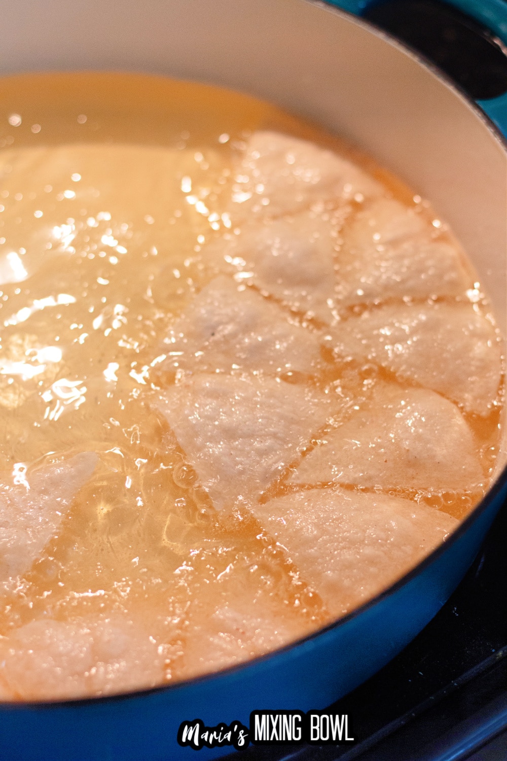 homemade tortilla chips being fried in a pot of oil