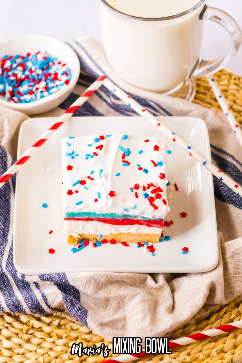 slice of no bake berry lush on a white square plate with a mug of milk behind it