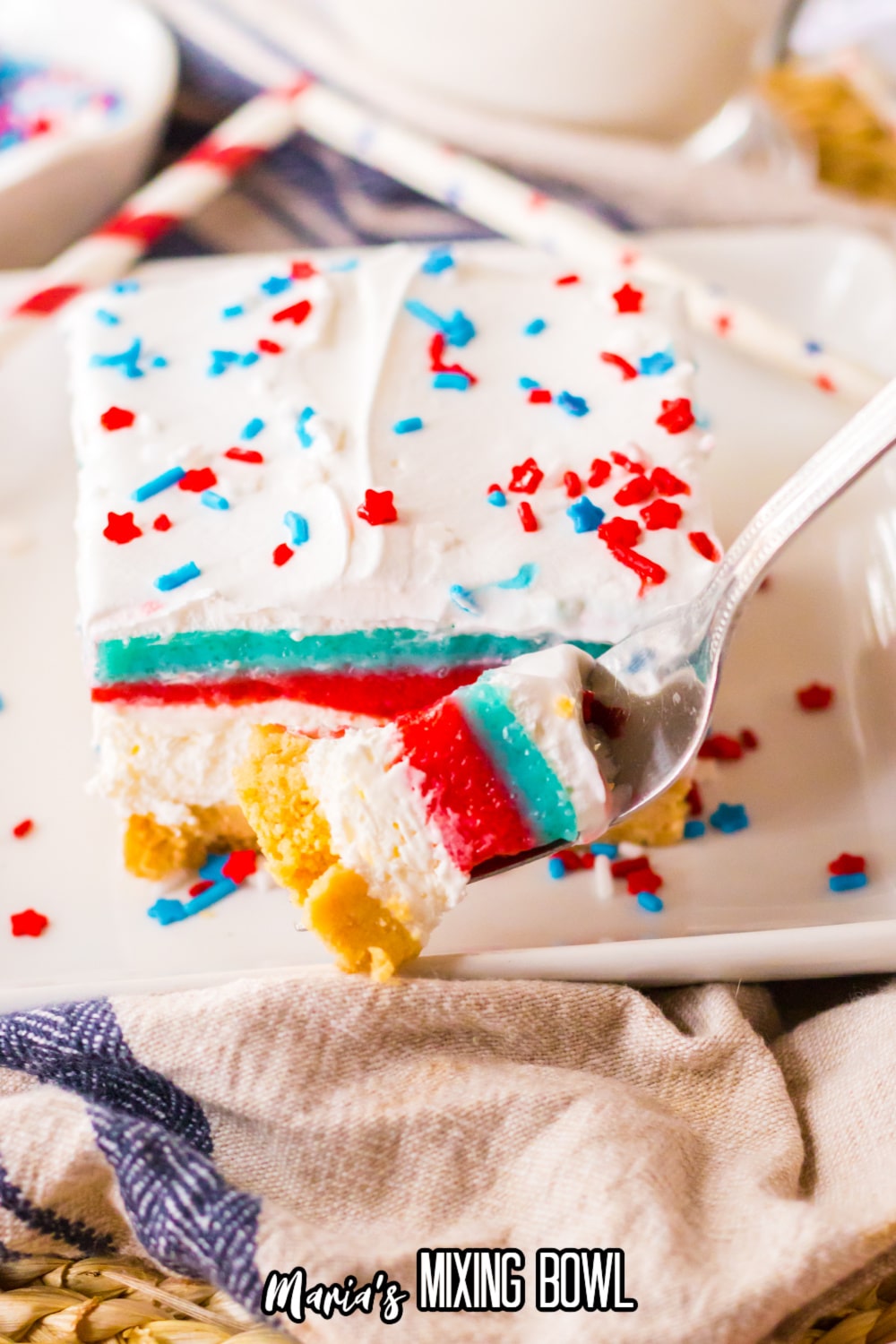 slice of no bake berry lush on a square plate with a bite on a fork in front of it