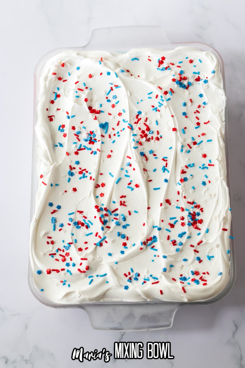 blue and red sprinkles being added to the top of the berry lush in a glass baking dish