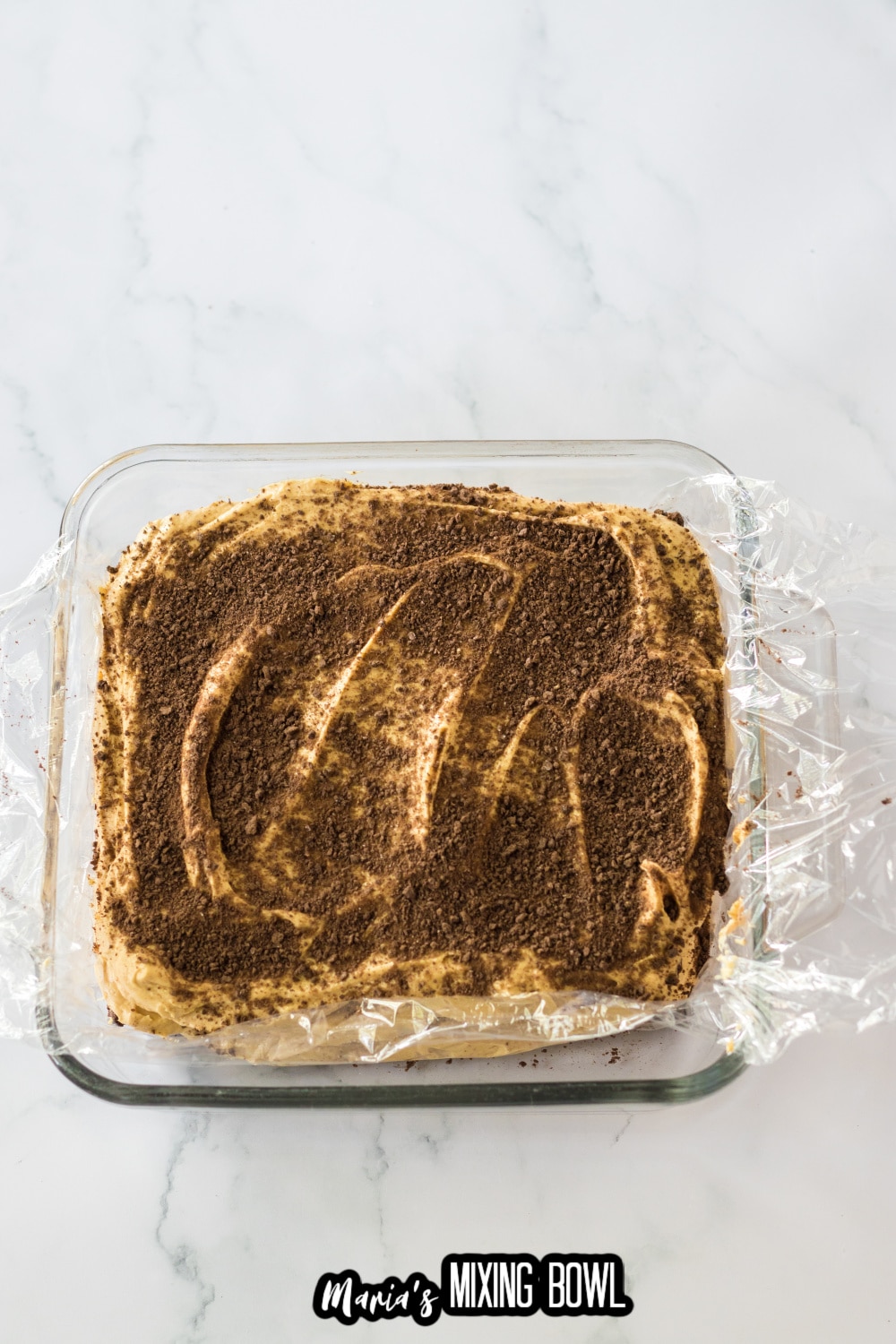 crushed graham crackers being sprinkled on top of an icebox cake