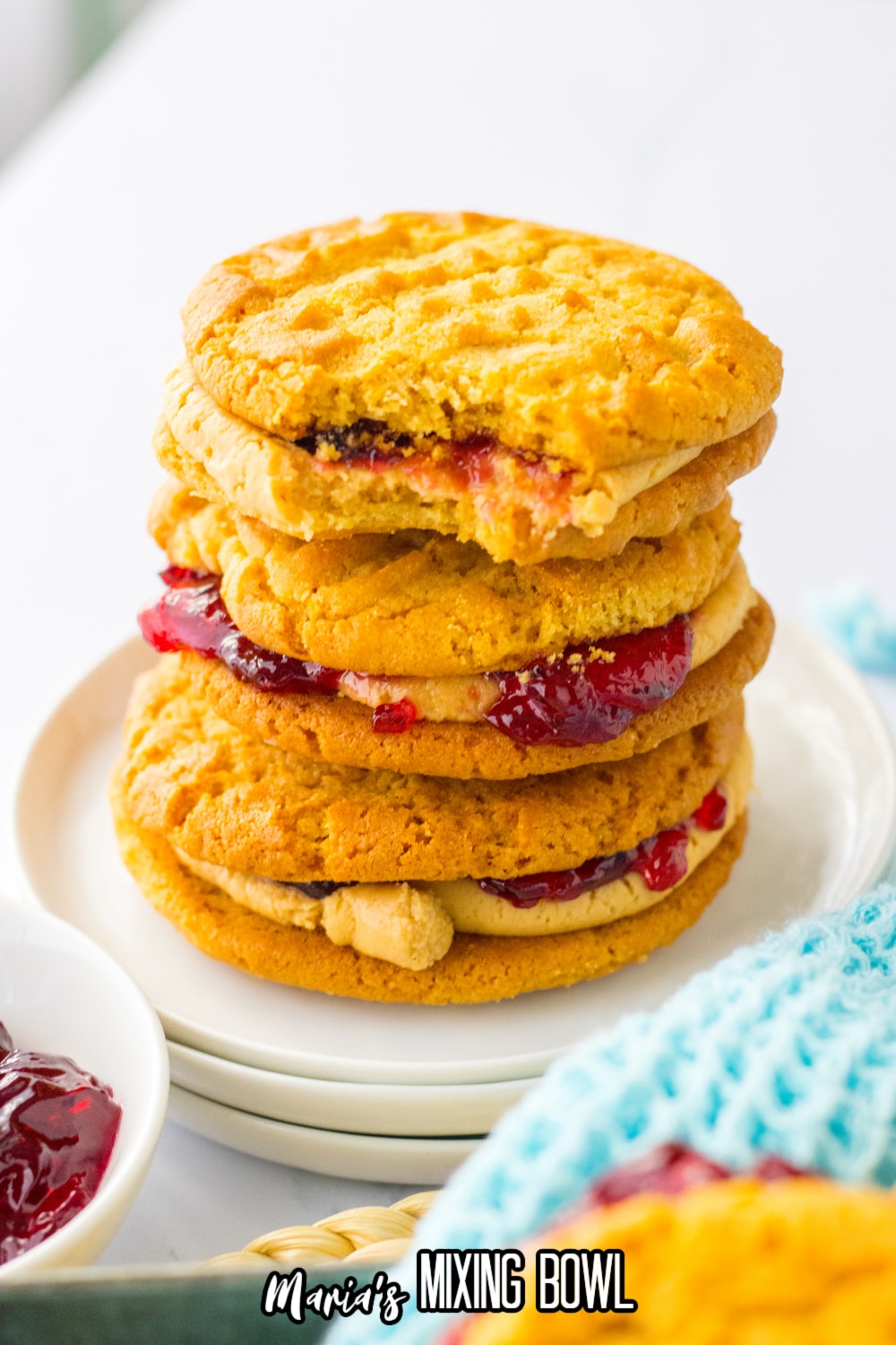 three peanut butter and jelly cookies stacked on a plate