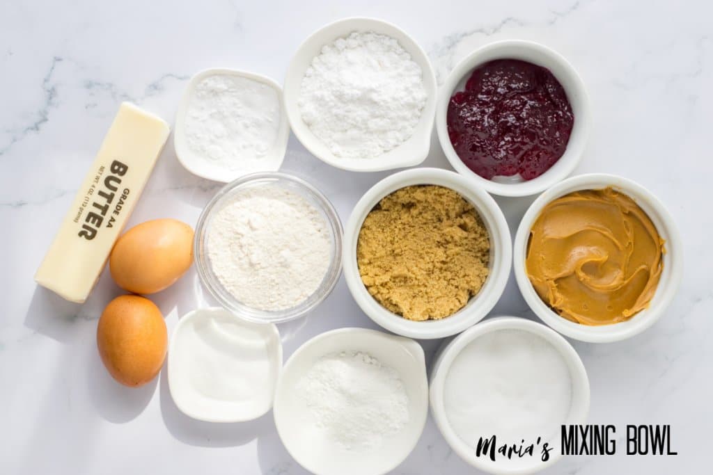 butter, eggs, flour, sugar, baking powder, salt, peanut butter and jelly on a marble background