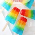 five rainbow popsicles on a white plate