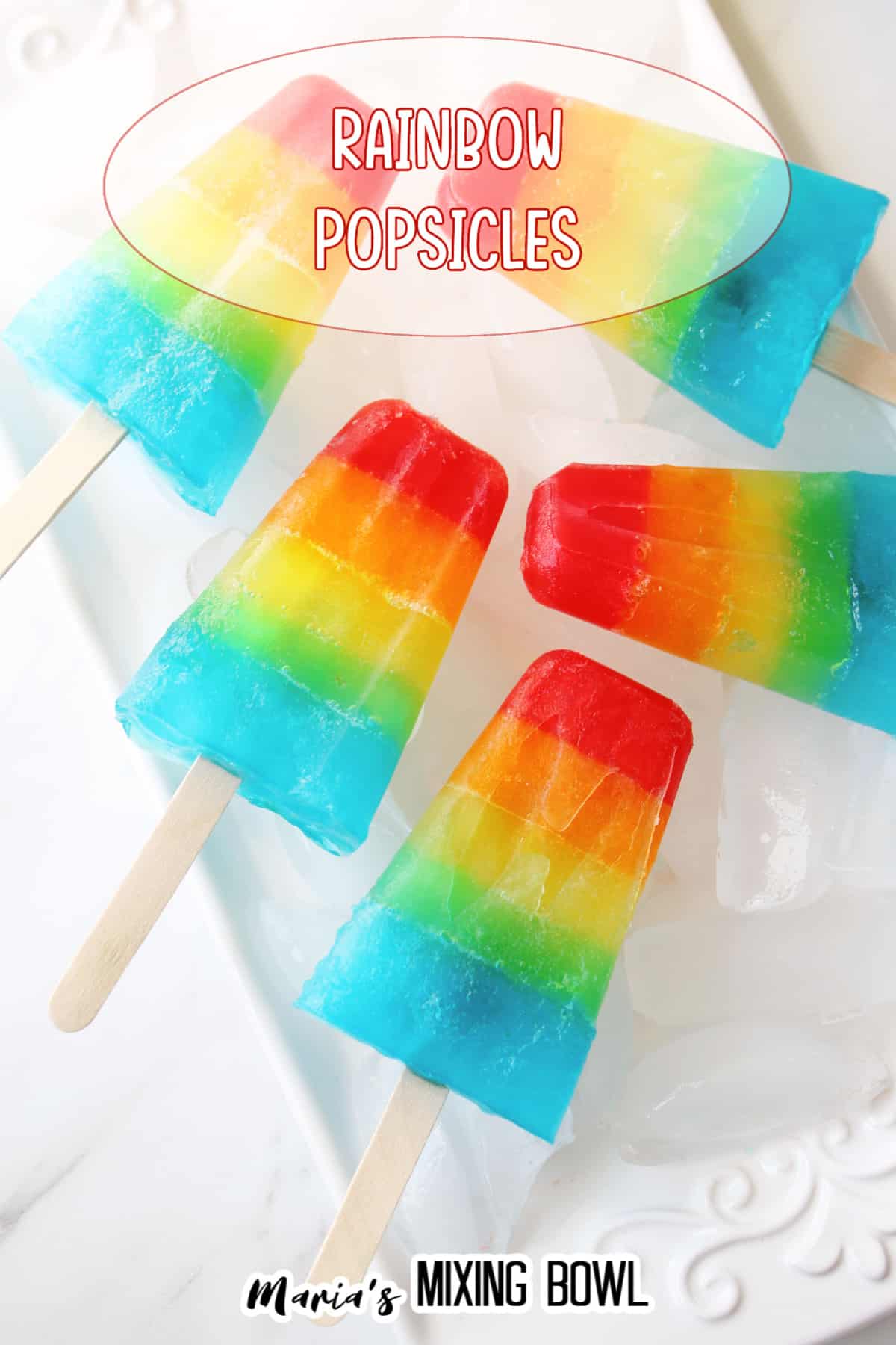 five rainbow popsicles on a white plate