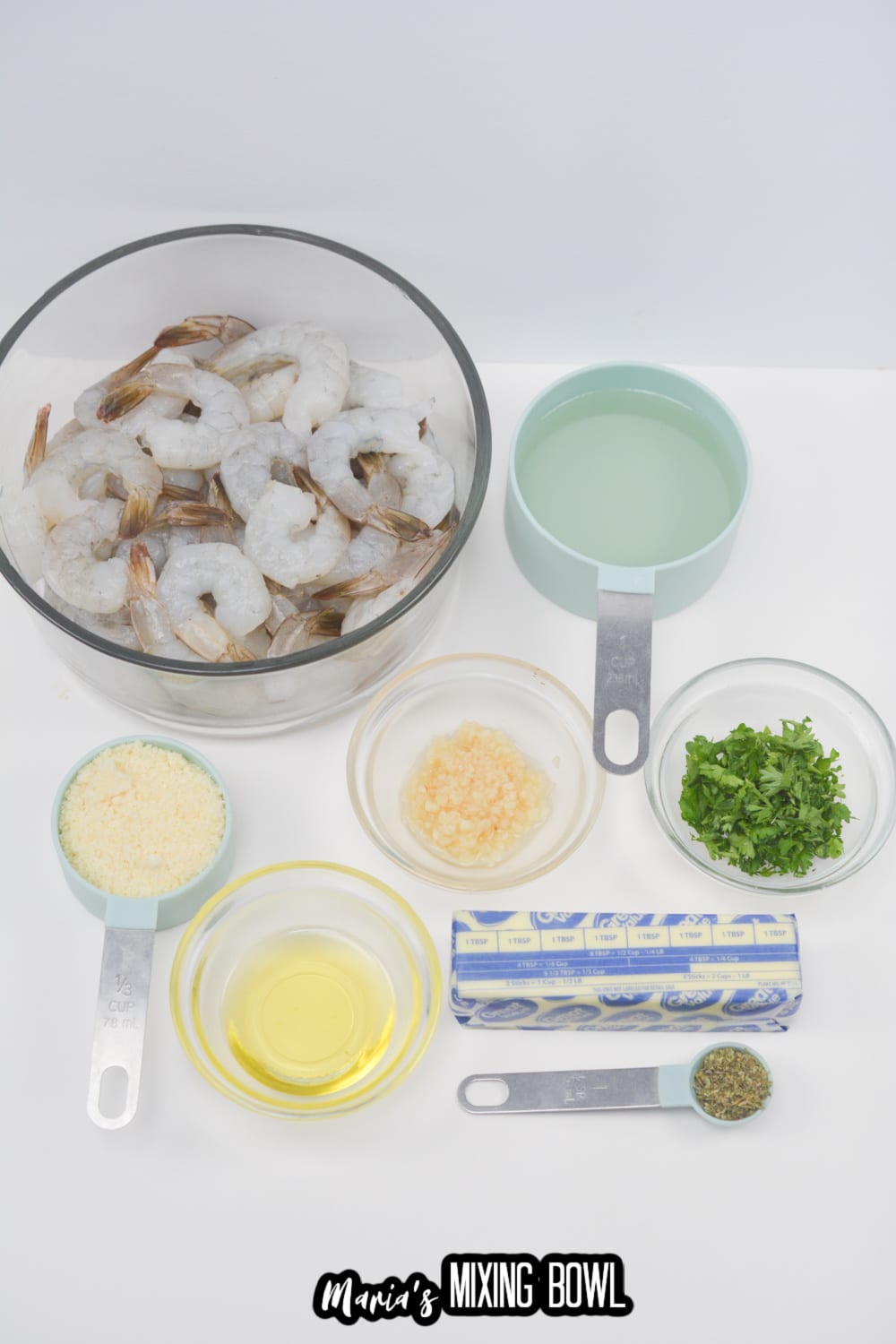 bowls of raw shrimp, butter, garlic, oil, lemon juice, italian seasoning on a white background