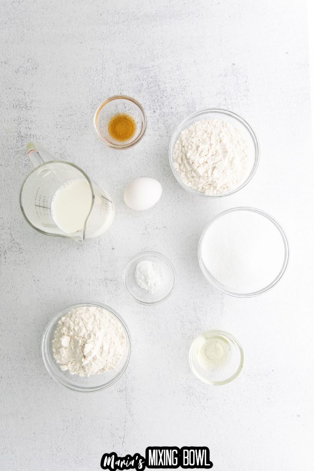 flour, sugar, baking soda, salt, egg, milk, and vanilla extract on a white background