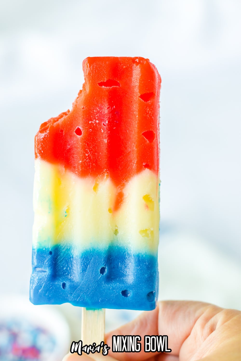 red white and blue pudding pop with a bite missing held in the air