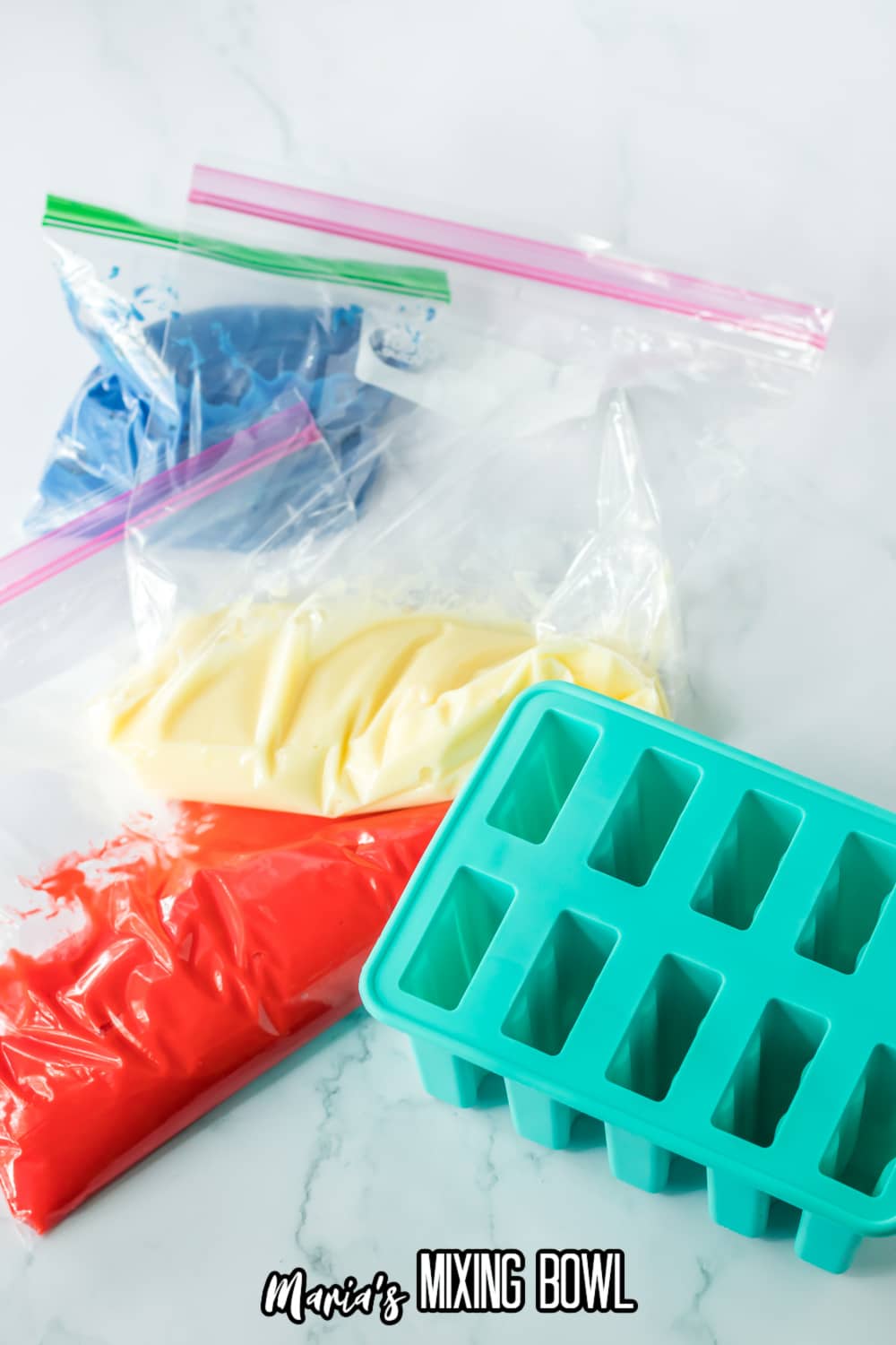 blue pudding, white pudding, and red puddling in sandwich bags and next to a popsicle mold