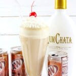 milkshake glass filled with a root beer float topped with whipped cream and a cherry