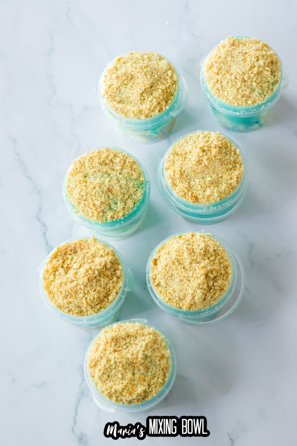 graham crackers being sprinkled on buckets filled with dessert