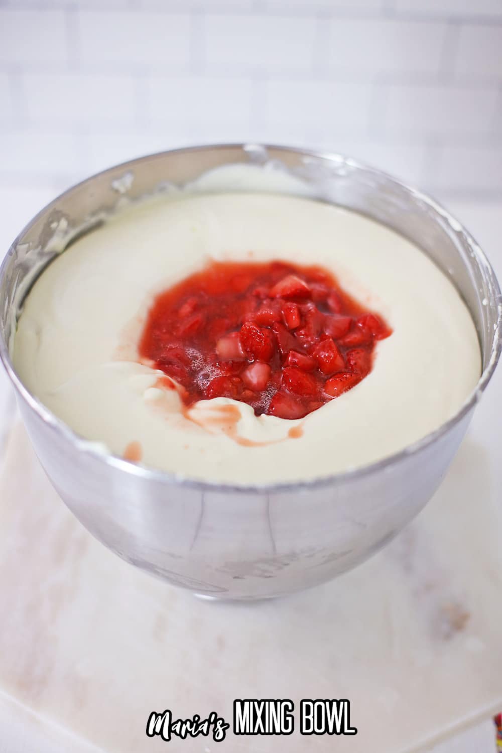 cheesecake batter and strawberries in a stainless steel mixing bowl