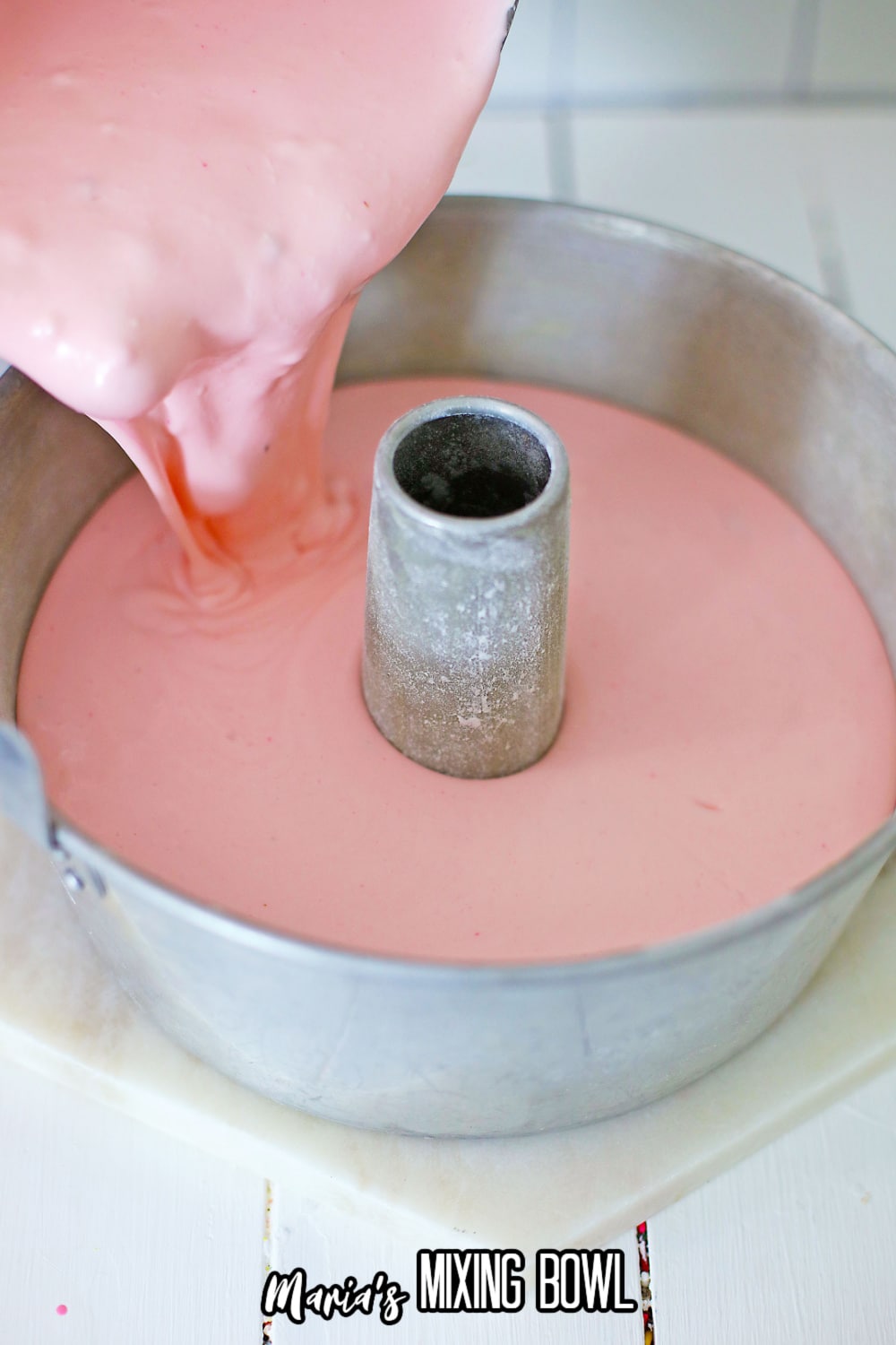 cheesecake batter being poured into a tube bundt pan